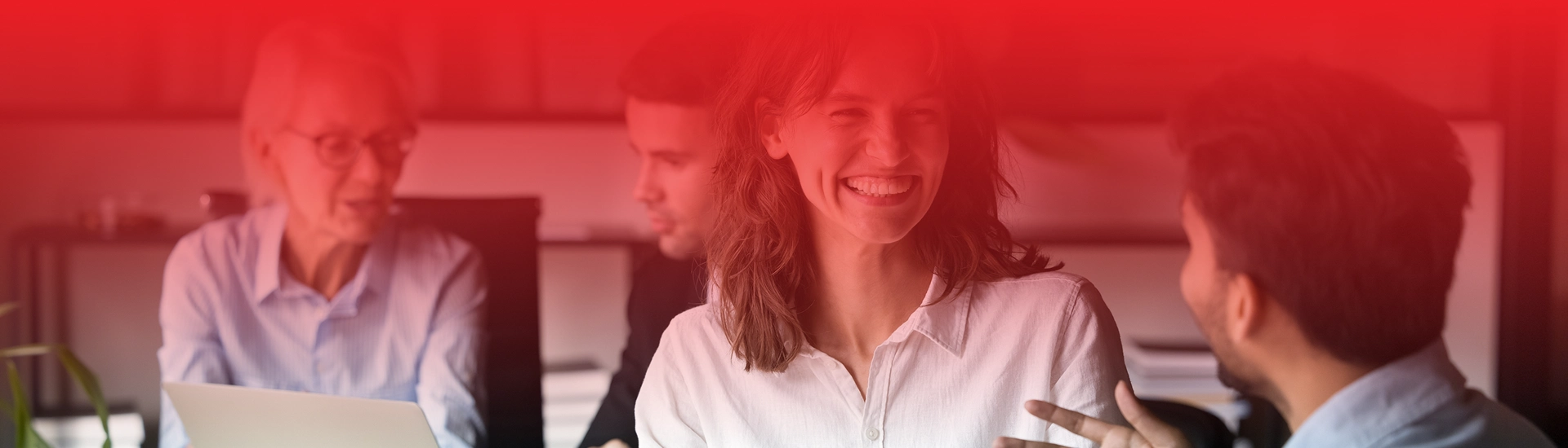 Grupa osób rozmawia ze sobą w biurze, kobieta na pierwszym planie uśmiecha się.